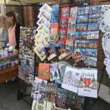 Stoisko z pamiątkami na gdansk market: pocztówki, magnesy i kubki z widokami miasta.