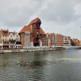 Gdańsk Żuraw, zabytkowy dźwig portowy, góruje nad malowniczą nadbrzeżną zabudową.