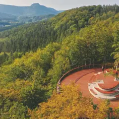 Drewniane wierze widokowe z amfiteatrem otoczone jesiennym lasem. W oddali góry i dolina.