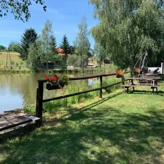 Urokliwe miejsce nad potokiem grzędy. Drewniane ławki i stoły zapraszają do odpoczynku, a kwitnące kwiaty dodają kolorytu.