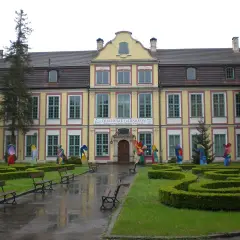 Pałac Opatów w Oliwie, otoczony zielenią i kolorowymi rzeźbami, zaprasza do zwiedzania.