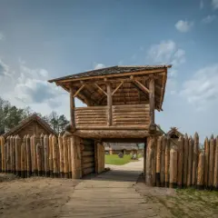 Drewniana wieża strażnicza i palisada. W oddali widać chaty. Sławutowo atrakcje przenoszą w czasy dawnych Słowian.