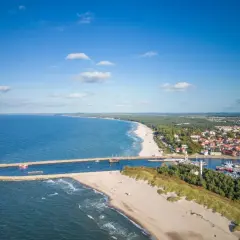 Widok na port i plażę w Ustce. Warto zobaczyć to malownicze wybrzeże Bałtyku z falochronami i kolorowymi łodziami.
