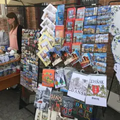 Stoisko z pamiątkami na gdansk market: pocztówki, magnesy i kubki z widokami miasta.