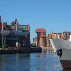 Widok na Motławę w Gdańsku. Na pierwszym planie biały dziób statku, w tle zabytkowe kamienice i Żuraw. Gdańsk starówka zachwyca.