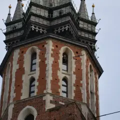Wieża Kościoła Mariackiego w Krakowie, z cegły i kamienia, z charakterystycznymi oknami i zdobieniami.