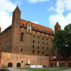 Gotycki zamek, duma kociewie miasta, z czerwonej cegły, z wieżami i czerwonym dachem, pod błękitnym niebem.