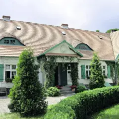 Urokliwy sikorzyno dworek z zielonymi okiennicami i pnączami.