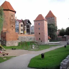 Wieże zamkowe w Chojnicach, Kaszuby, z placem zabaw i zielenią.