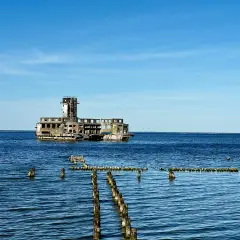 Ruiny torpedowni w Helu, betonowy moloch na tle błękitnego nieba i spokojnego morza.