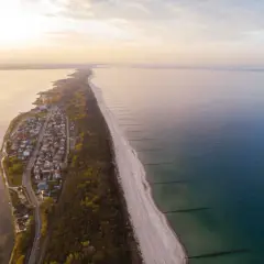 Widok z lotu ptaka na Chałupy, gdzie urokliwe domki letniskowe sąsiadują z piaszczystą plażą i lasem. Idealne miejsce na wakacyjne atrakcje.