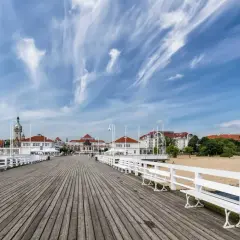 Drewniane molo w Sopocie, z widokiem na plażę i zabytkowe budynki. To popularne sopockie atrakcje, idealne na spacer.