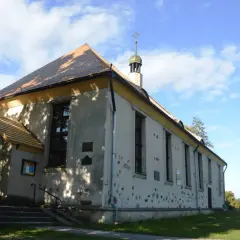 Cerkiew w Bytach, prosta budowla z charakterystycznym dachem i wieżyczką, otoczona zielenią.