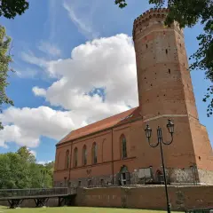 Chojnice zamek krzyżacki, ceglana wieża i budynek muzeum pod błękitnym niebem z chmurami.