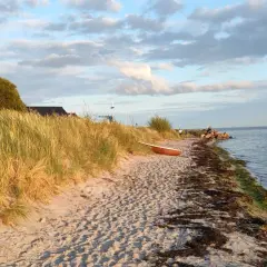 Piękna plaża w Kuźnicy, z łódką na piasku i trawami na wydmach. Idealne miejsce na relaks i podziwianie widoków. Kuźnica atrakcje to przede wszystkim spokój i bliskość natury.