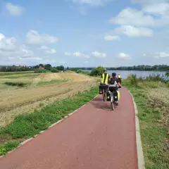 Rowerzyści na tczewskiej trasie podziwiają krajobraz z polami i rzeką.