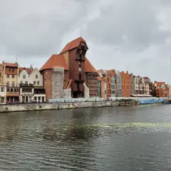 Gdańsk Żuraw, zabytkowy dźwig portowy, góruje nad malowniczą nadbrzeżną zabudową.