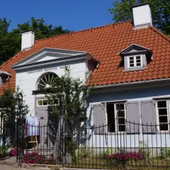 Jasnoniebieski dworek Sierakowskich z czerwonym dachem, ozdobiony napisem "Towarzystwo Przyjaciół Sopotu".