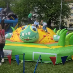 Dzieci bawią się na dmuchanym placu zabaw w kształcie gąsienicy. To świetne **nowęcin atrakcje** dla najmłodszych.
