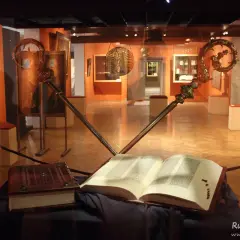 Otwarta biblia gutenberga pelplin, obok zamknięta księga i dwa ozdobne pastorały w muzeum.
