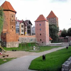 Dawne baszty i mury obronne, gdzie są Chojnice, tworzą malowniczy krajobraz z placem zabaw dla dzieci.