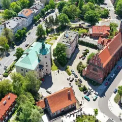 Słupsk atrakcje: zamek Książąt Pomorskich z zielonym dachem i ceglany kościół z wieżą.