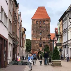 Spacer po urokliwej uliczce z kolorowymi kamienicami, w tle majestatyczna brama człuchowska.