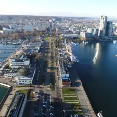 Widok z lotu ptaka na Skwer Kościuszki w Gdyni z mariną, statkami i nowoczesną architekturą.