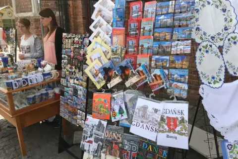 Stoisko z pamiątkami na gdansk market: pocztówki, magnesy i kubki z widokami miasta.