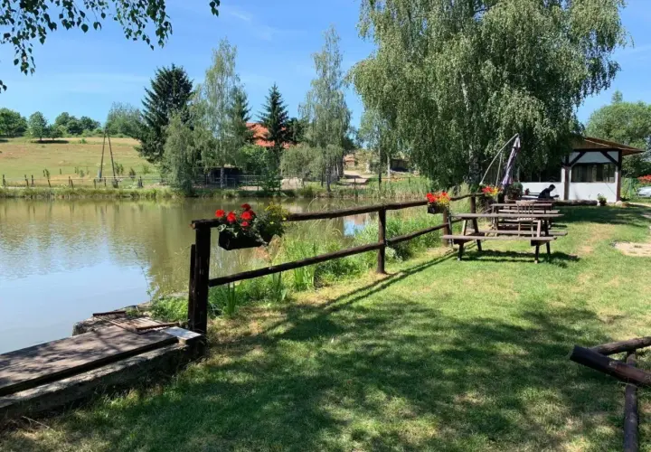 Urokliwe miejsce nad potokiem grzędy. Drewniane ławki i stoły zapraszają do odpoczynku, a kwitnące kwiaty dodają kolorytu.