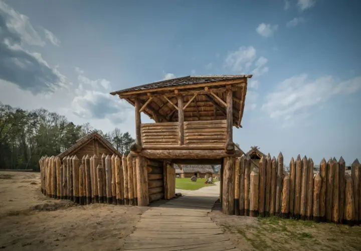 Drewniana wieża strażnicza i palisada. W oddali widać chaty. Sławutowo atrakcje przenoszą w czasy dawnych Słowian.