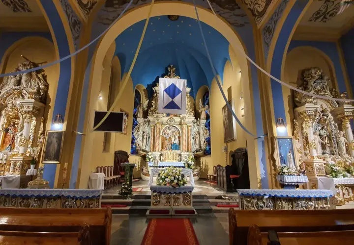 Wnętrze kościoła w Jastarni, bogato zdobiony ołtarz główny z figurami świętych, niebieskie sklepienie z gwiazdami i złote detale tworzą uroczystą atmosferę.