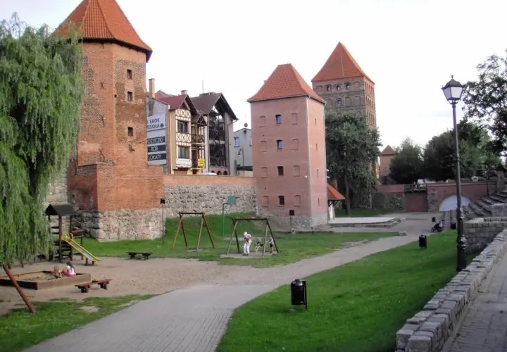 Wieże zamkowe w Chojnicach, Kaszuby, z placem zabaw i zielenią.