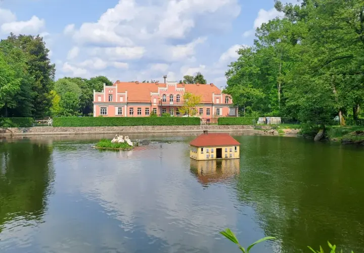 Wejherowo Park Majkowskiego: urokliwy staw z pływającym domkiem i łabędziami, w tle różowy pałacyk. Idealne miejsce na rodzinne imprezy.