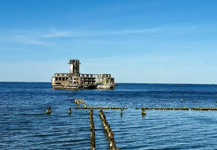 Ruiny torpedowni w Helu, betonowy moloch na tle błękitnego nieba i spokojnego morza.