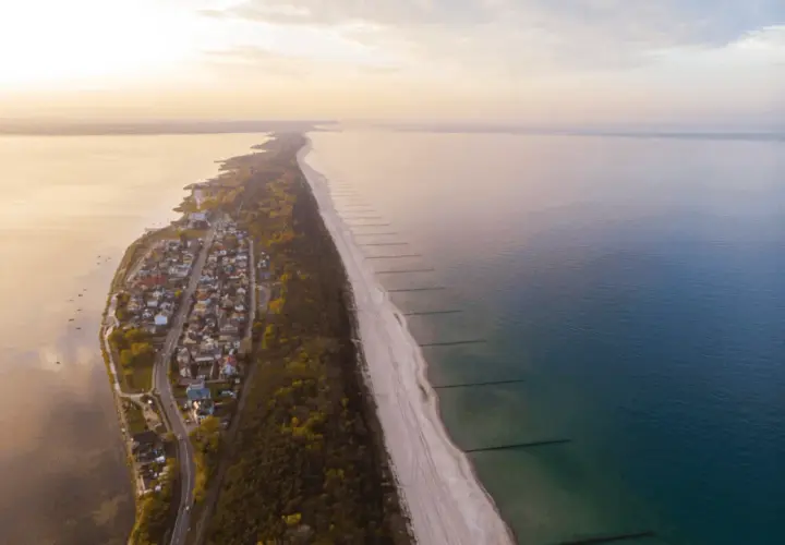 Widok z lotu ptaka na Chałupy, gdzie urokliwe domki letniskowe sąsiadują z piaszczystą plażą i lasem. Idealne miejsce na wakacyjne atrakcje.