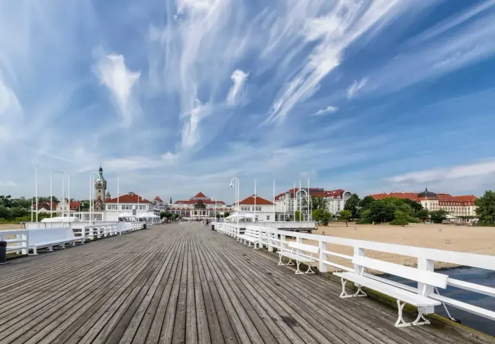 Drewniane molo w Sopocie, z widokiem na plażę i zabytkowe budynki. To popularne sopockie atrakcje, idealne na spacer.