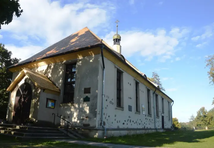Cerkiew w Bytach, prosta budowla z charakterystycznym dachem i wieżyczką, otoczona zielenią.
