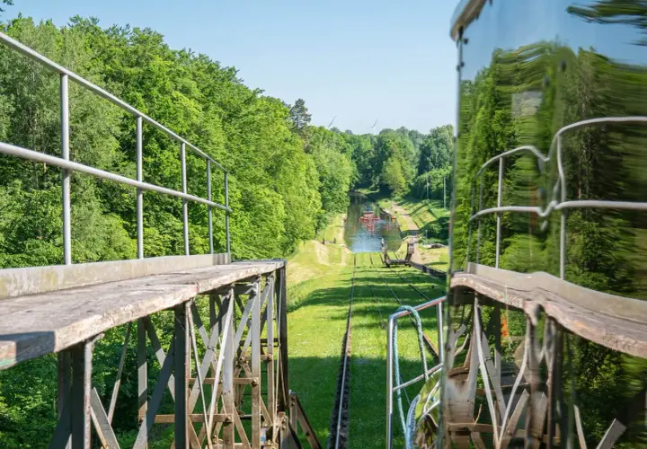 Widok z wagonu kolejki linowej na kanał wodny otoczony zielenią. W oddali widać wiatraki. Mątowy wielkie wrażenie.