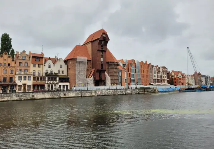 Gdańsk Żuraw, zabytkowy dźwig portowy, góruje nad malowniczą nadbrzeżną zabudową.