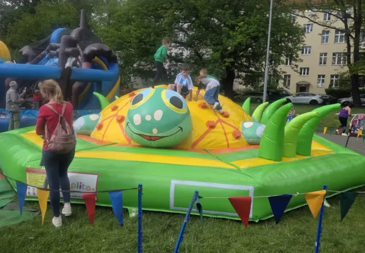Dzieci bawią się na dmuchanym placu zabaw w kształcie gąsienicy. To świetne **nowęcin atrakcje** dla najmłodszych.