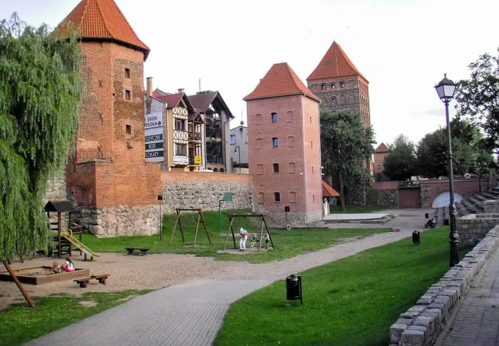 Dawne baszty i mury obronne, gdzie są Chojnice, tworzą malowniczy krajobraz z placem zabaw dla dzieci.