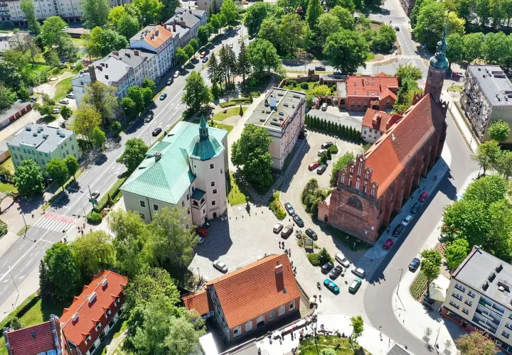 Słupsk atrakcje: zamek Książąt Pomorskich z zielonym dachem i ceglany kościół z wieżą.