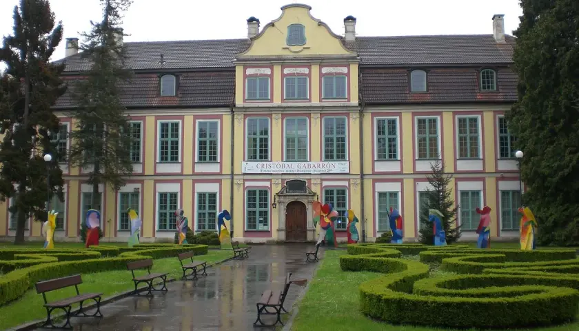 Pałac Opatów w Oliwie, otoczony zielenią i kolorowymi rzeźbami, zaprasza do zwiedzania.