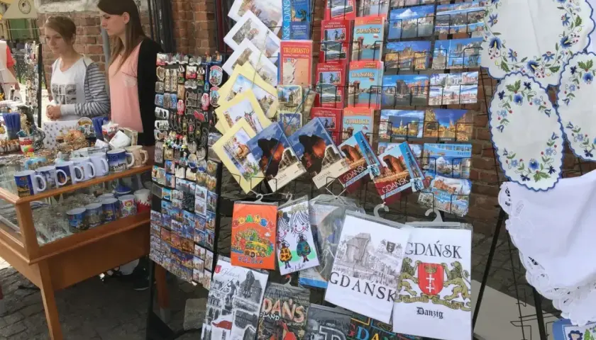 Stoisko z pamiątkami na gdansk market: pocztówki, magnesy i kubki z widokami miasta.