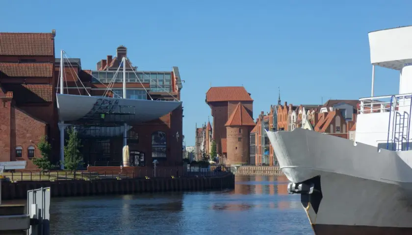 Widok na Motławę w Gdańsku. Na pierwszym planie biały dziób statku, w tle zabytkowe kamienice i Żuraw. Gdańsk starówka zachwyca.