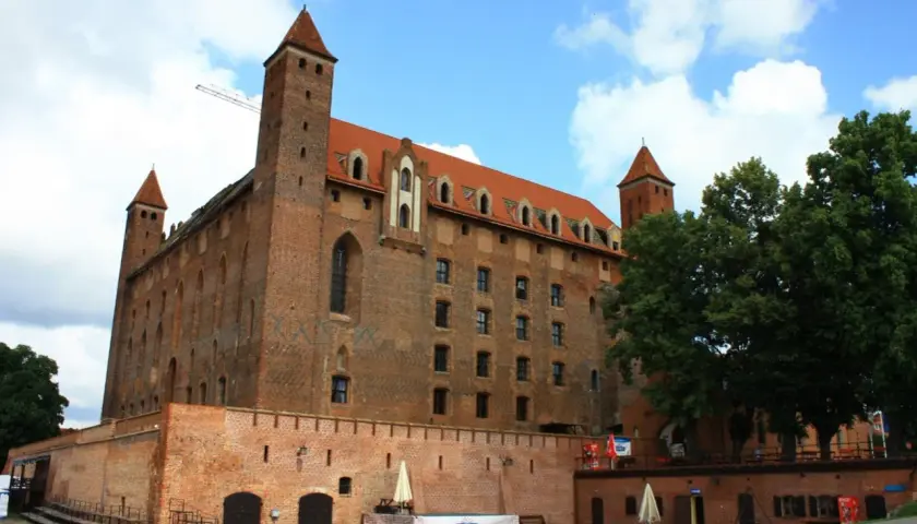 Gotycki zamek, duma kociewie miasta, z czerwonej cegły, z wieżami i czerwonym dachem, pod błękitnym niebem.
