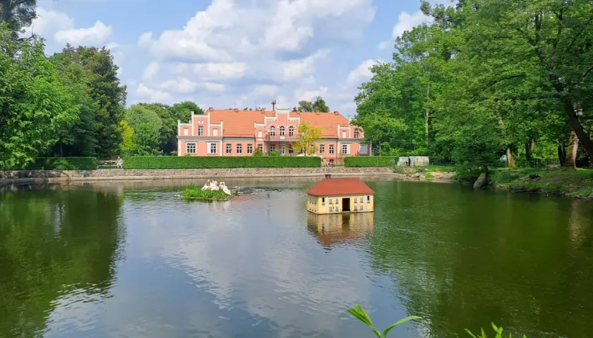 Wejherowo Park Majkowskiego: urokliwy staw z pływającym domkiem i łabędziami, w tle różowy pałacyk. Idealne miejsce na rodzinne imprezy.
