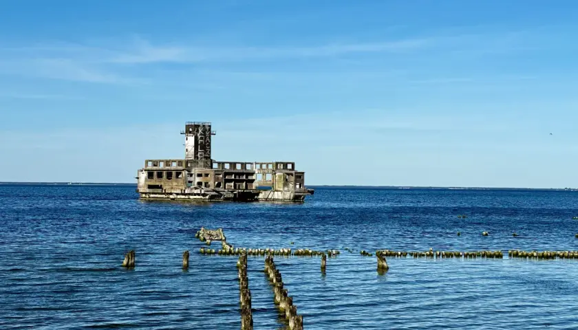 Ruiny torpedowni w Helu, betonowy moloch na tle błękitnego nieba i spokojnego morza.