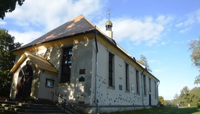 Cerkiew w Bytach, prosta budowla z charakterystycznym dachem i wieżyczką, otoczona zielenią.